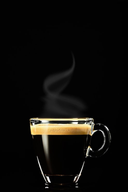 Bezpłatny plik Zdjęcie espresso na ciemnym tle, para unosi się nad kawą. kawa na śniadanie we włoskiej kawiarni, ujęcie pionowe, selektywne skupienie