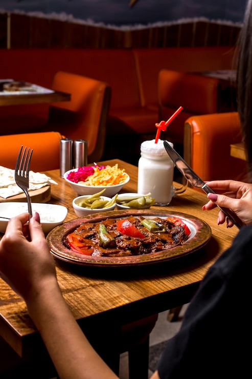 Bezpłatny plik Zdjęcie kobieta jest serwowana kebab iskender w miedzianym talerzu z marynowanym jogurtem i ajranem