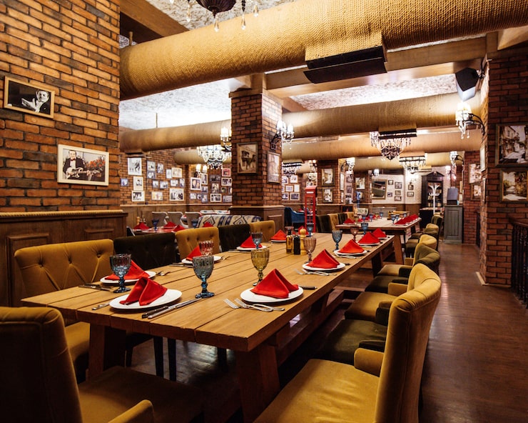 Bezpłatny plik Zdjęcie sala restauracyjna z czerwonymi murami z cegły, drewnianymi stołami i rurami na suficie