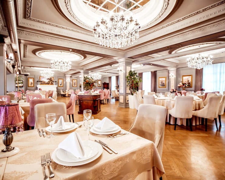 Bezpłatny plik Zdjęcie sala restauracyjna z okrągłymi i kwadratowymi stołami, krzesłami i roślinami