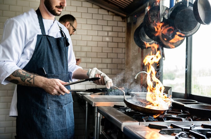 Bezpłatny plik Zdjęcie szef kuchni gotuje jedzenie w kuchni restauracji