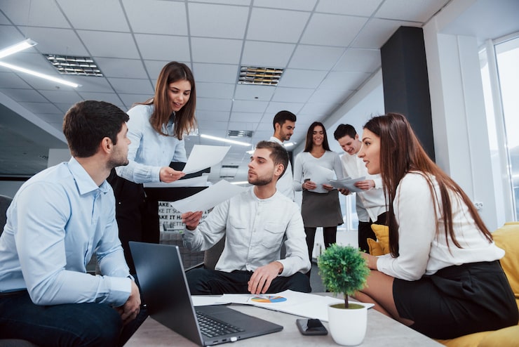 Foto gratuito ambiente de trabajo pero divertido. grupo de jóvenes autónomos en la oficina conversando y sonriendo