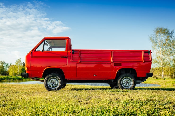 Photo Gratis bidikan close-up truk merah di ladang hijau di samping air