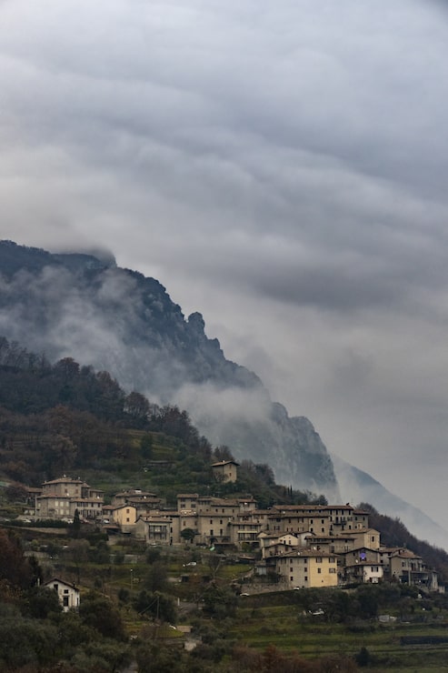 Photo Gratis bidikan vertikal sebuah desa kecil italia di gunung yang dikelilingi oleh kabut