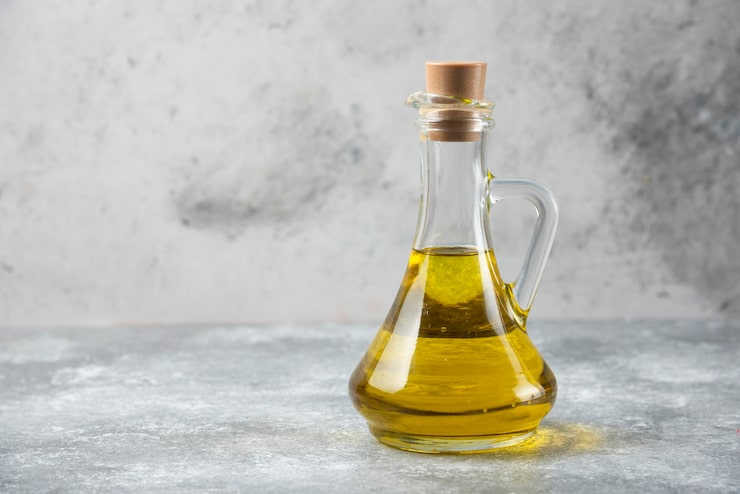 Foto gratuito botella de aceite de oliva sobre mesa de mármol.