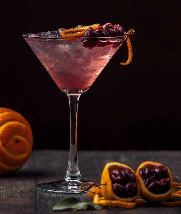 Foto gratuito cóctel de cereza adornado con cereza y cáscara de naranja y hielo