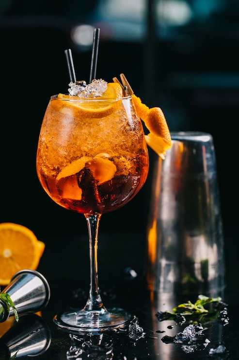Foto gratuito cóctel de naranja dentro de vidrio con cubitos de hielo picado y tuberías.