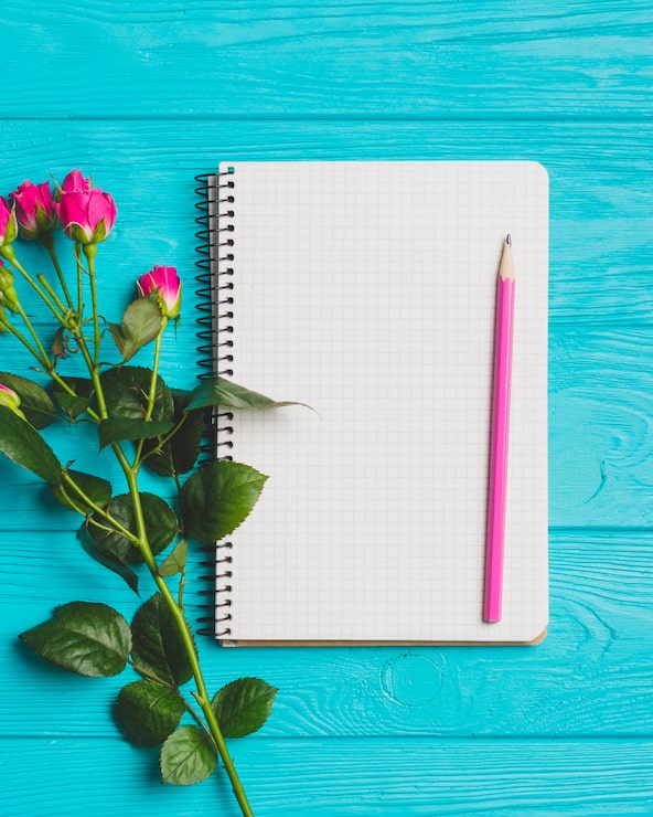 Foto gratuito cuaderno de primer plano cerca de rosas