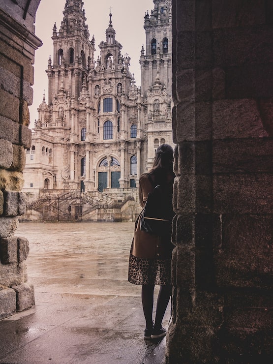 Foto gratuito disparo vertical de una elegante mujer en la catedral de santiago de compostela en españa en un día lluvioso