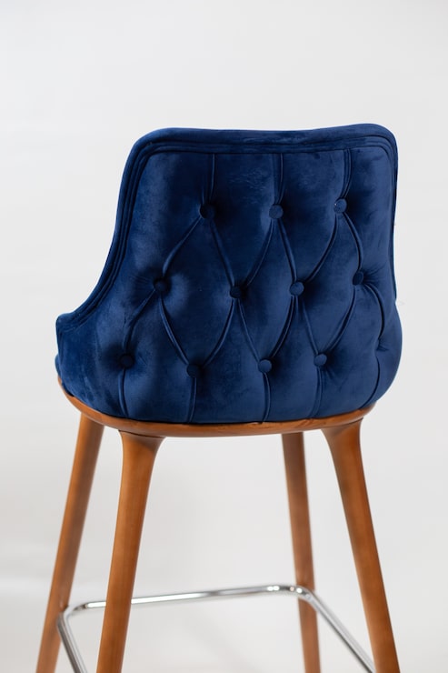 Foto gratuito disparo vertical de una silla azul con botones detrás de un fondo blanco.