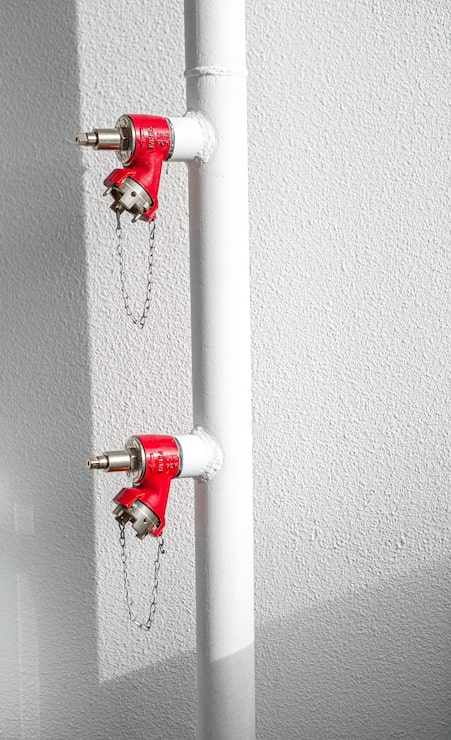 Foto gratuito extintor de fuego rojo en pared blanca