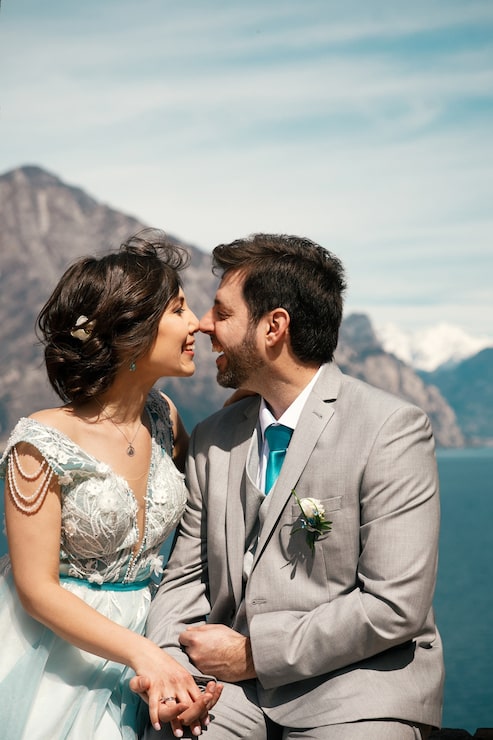 Foto gratuito feliz novia y el novio se detienen tiernamente de pie antes de hermoso paisaje de mar