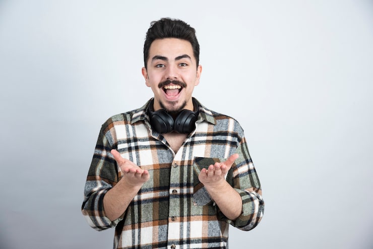 Photo Gratis foto pria tampan dengan headphone berdiri dan melihat ke dinding putih.
