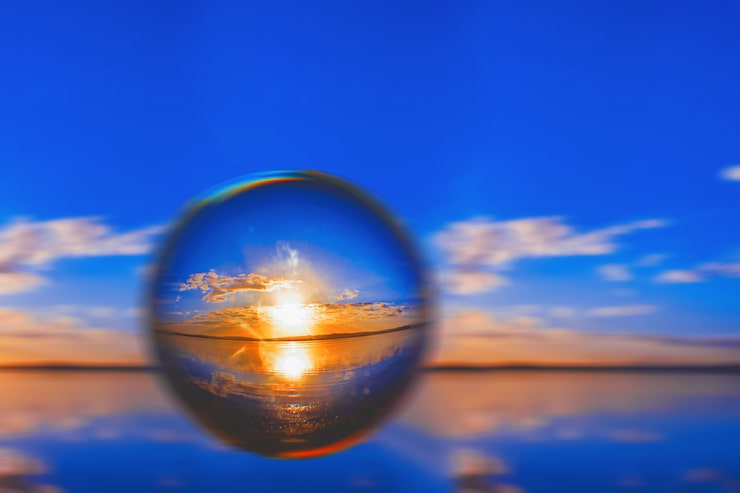 Photo Gratis fotografi bola lensa kreatif dari sinar matahari di cakrawala dengan awan di sekitar langit biru