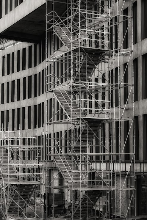 Foto gratuito fotografía vertical en escala de gris de una escalera fuera de un edificio utilizado para la reconstrucción