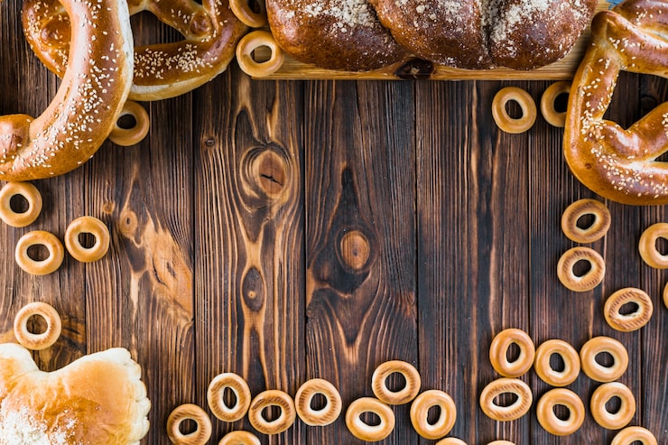 Foto gratuito frontera hecha con pan trenzado recién horneado, pretzels y panecillos en el fondo de madera