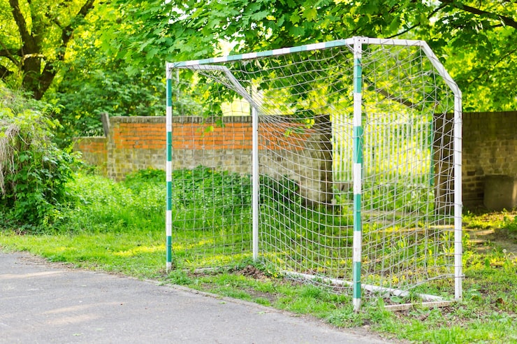 Photo Gratis gawang bola di lapangan sepak bola di taman yang dikelilingi pohon-pohon hijau.