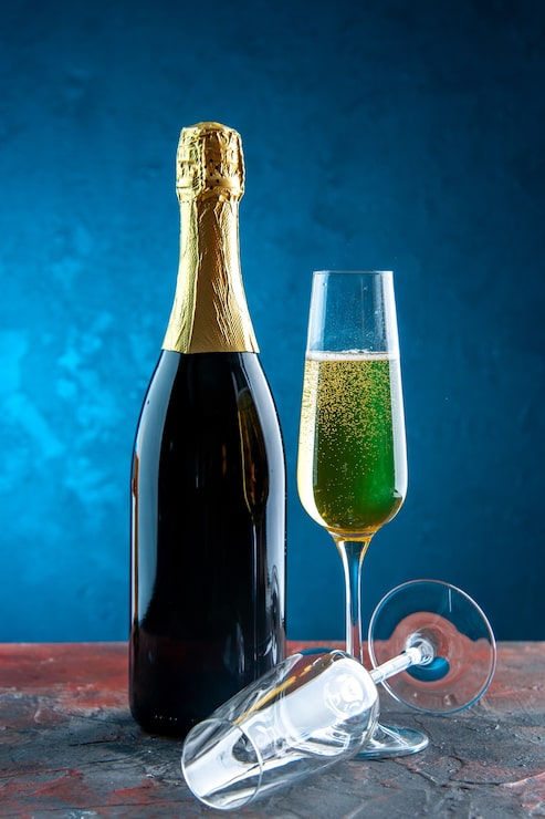 Photo Gratis gelas sampanye tampilan depan dengan botol pada foto alkohol minuman pesta perayaan warna biru tahun baru