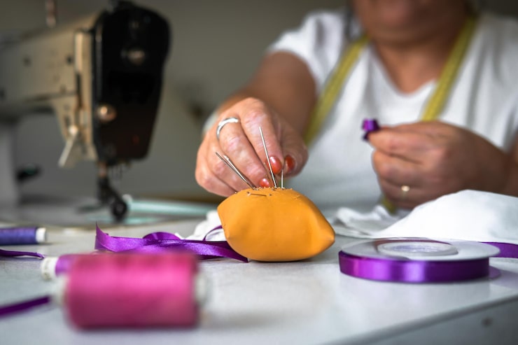 Foto gratuito hembra adulta cosiendo una cinta morada en una mascarilla en el taller de concienciación covid19