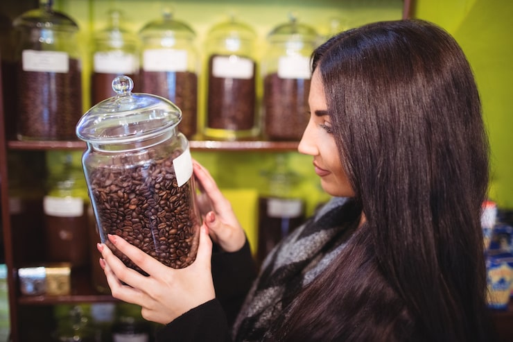 Foto gratuito hermosa mujer sosteniendo tarro de granos de café