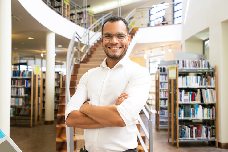 Foto gratuito hombre afroamericano sonriente que presenta en la biblioteca pública