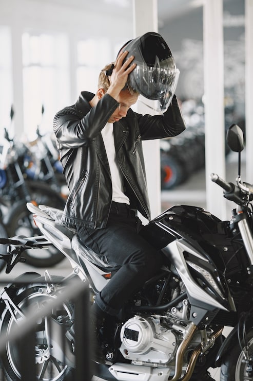 Foto gratuito el hombre eligió motocicletas en la tienda de motos. chico con chaqueta negra. hombre con casco.