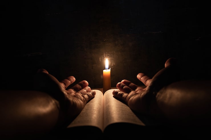 Foto gratuito hombres rezando en la biblia en las velas ligeras enfoque selectivo.