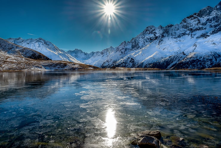 Foto gratuito impresionante toma de un hermoso lago congelado rodeado de montañas nevadas durante un día soleado