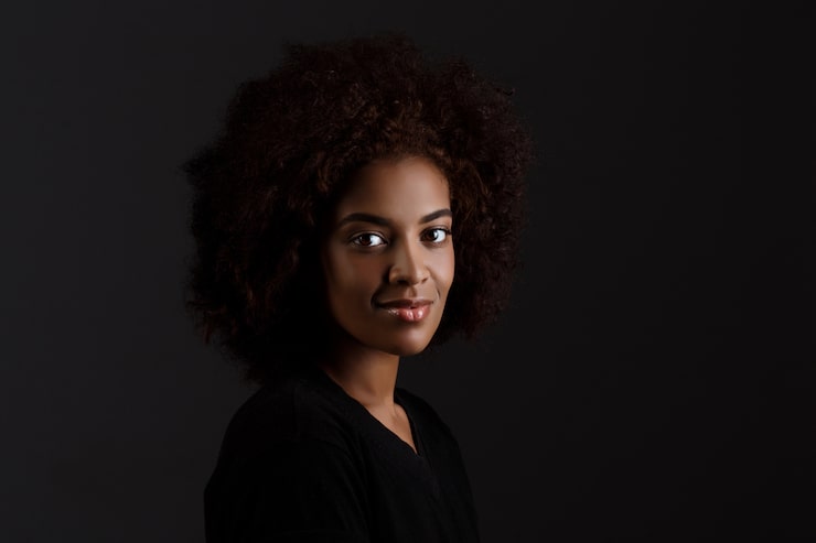 Foto gratuito joven y hermosa chica africana sonriendo sobre la pared oscura