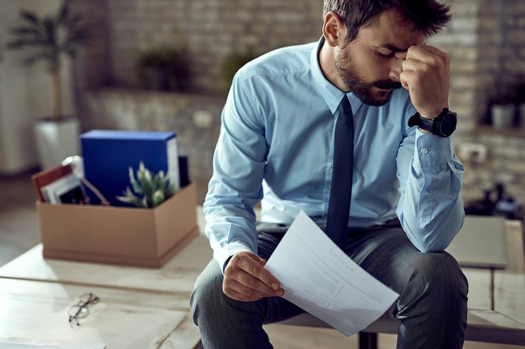 Foto gratuito joven hombre de negocios frustrado sosteniendo su cabeza de dolor después de ser despedido en el trabajo