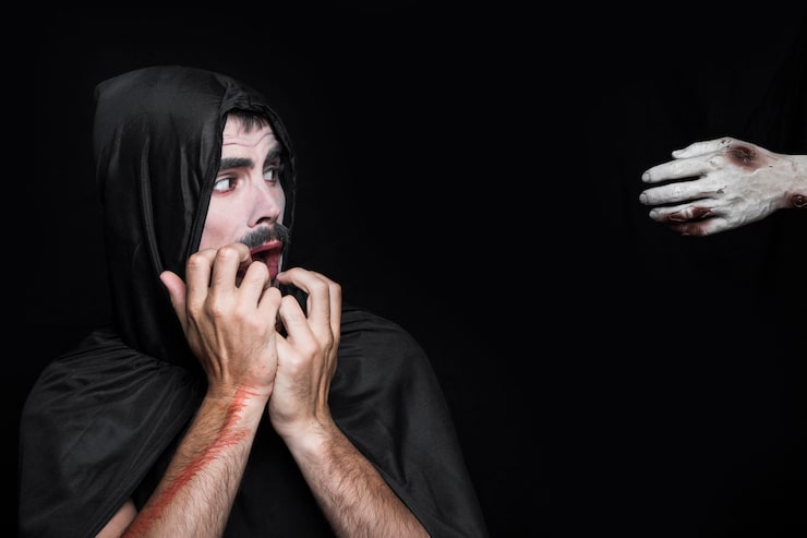 Foto gratuito joven en traje de halloween mirando la mano del cadáver