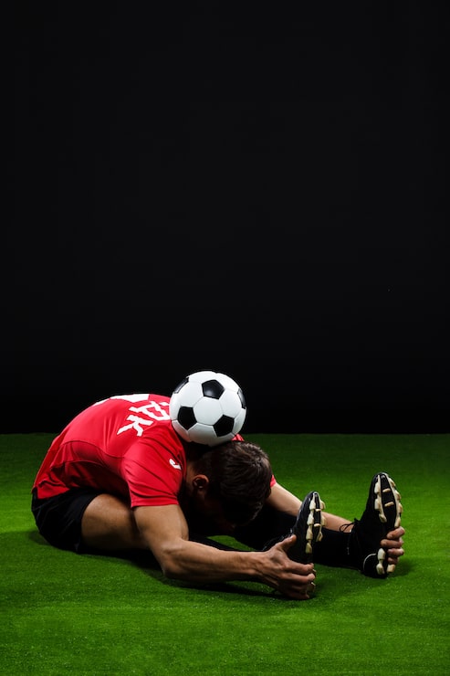 Foto gratuito jugador de fútbol que se extiende sobre césped con pelota