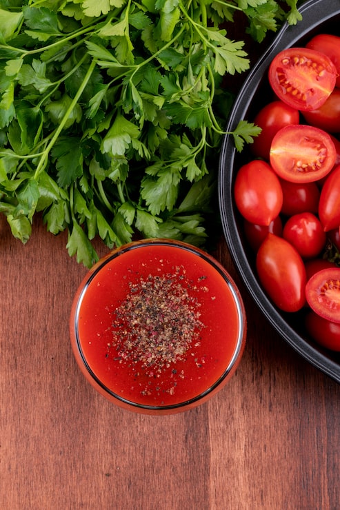Foto gratuito jugo de tomate en vidrio y tomates cherry en vista superior de pan
