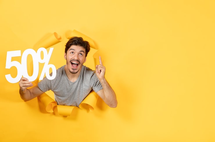 Foto gratuito macho joven con cartel de inscripción sobre fondo amarillo rasgado chico venta de compras interior
