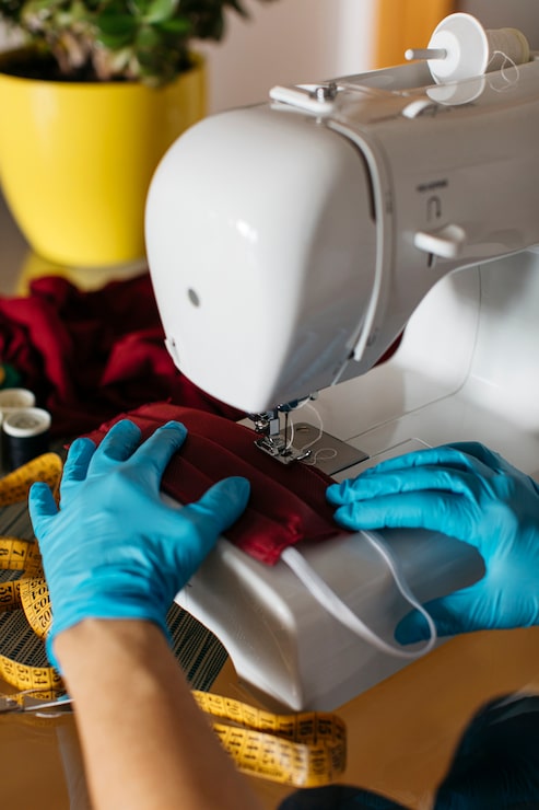 Foto gratuito manos con guantes terminando una mascarillas de tela