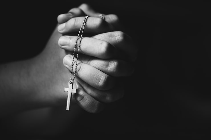 Foto gratuito manos sosteniendo la cruz mientras reza.