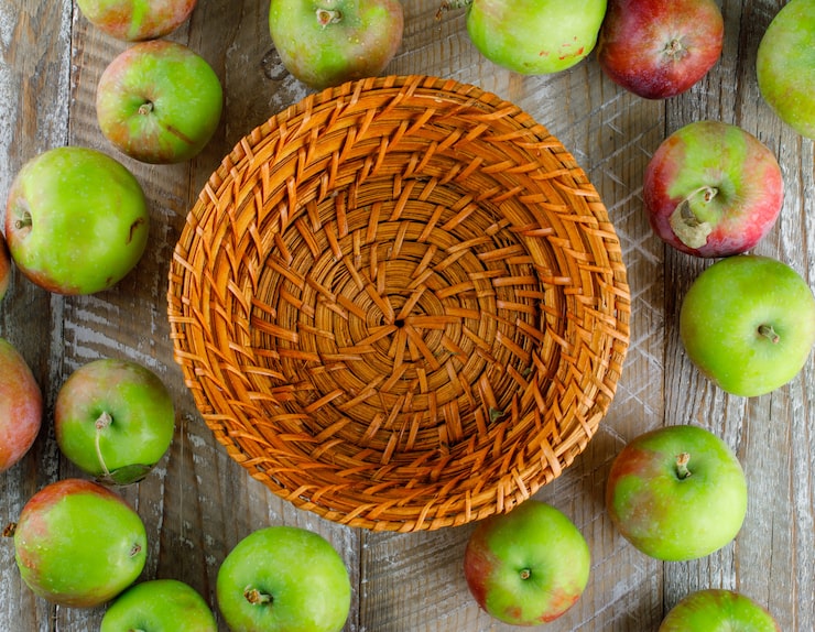 Foto gratuito manzanas esparcidas con canasta vacía en madera