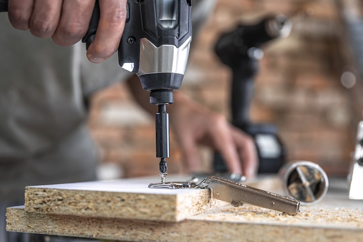 Photo Gratis memasang sekrup self-tapping ke dalam lubang pengencang logam pada strip kayu menggunakan obeng, pekerjaan seorang tukang kayu.