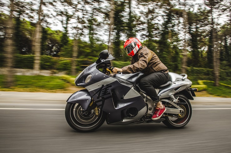 Foto gratuito moto de alta velocidad en bicicleta por la carretera a través del bosque