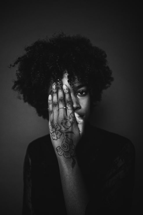 Foto gratuito mujer con cabello afro negro y tatuaje en su mano