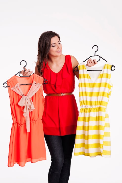 Foto gratuito mujer eligiendo entre vestido de rayas y naranja