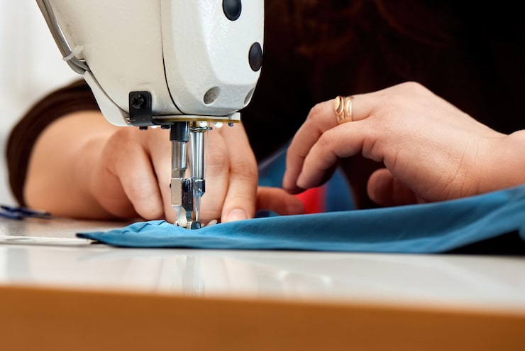 Foto gratuito mujer trabajando en una máquina de coser con tela azul