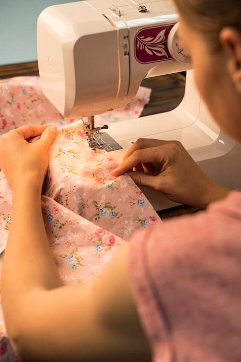 Foto gratuito mujer usando la máquina de coser en patrón floral