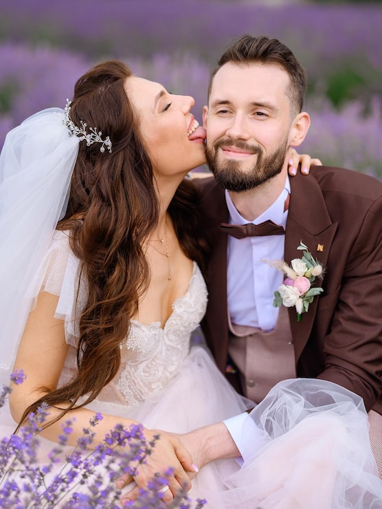 Foto gratuito mujer en vestido de novia tocando la mejilla del hombre mientras posa en el campo