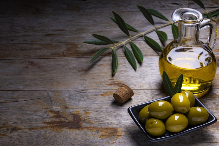 Foto gratuito olivas de aspecto sabroso, aceite de oliva virgen extra y hojas de oliva sobre un fondo de madera oscura