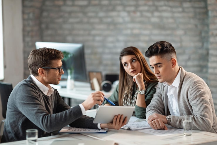 Foto gratuito pareja joven usando tableta digital con su agente de seguros durante las consultas en la oficina