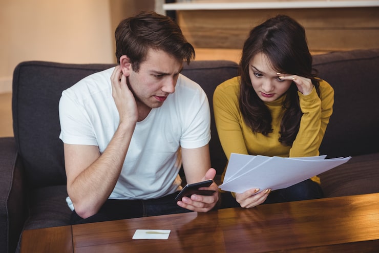 Foto gratuito pareja sentada en un sofá discutiendo con documentos financieros en el salón