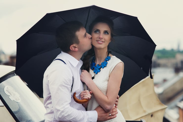 Foto gratuito pareja soñadora plantea bajo el paraguas en el techo