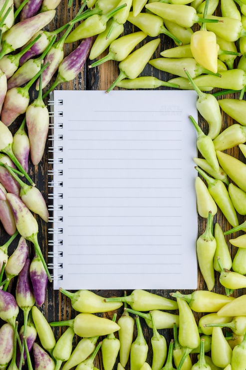 Foto gratuito pimientos maduros con cuaderno de espiral en madera,