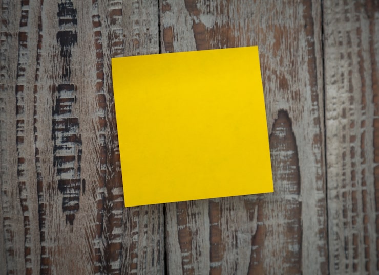Foto gratuito post-it amarillo pegado en una pared